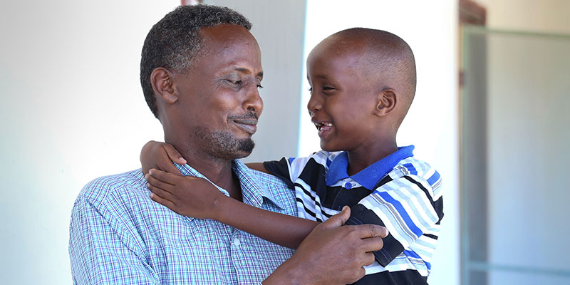 Shariif und sein Vater Mohammad lächeln und umarmen sich