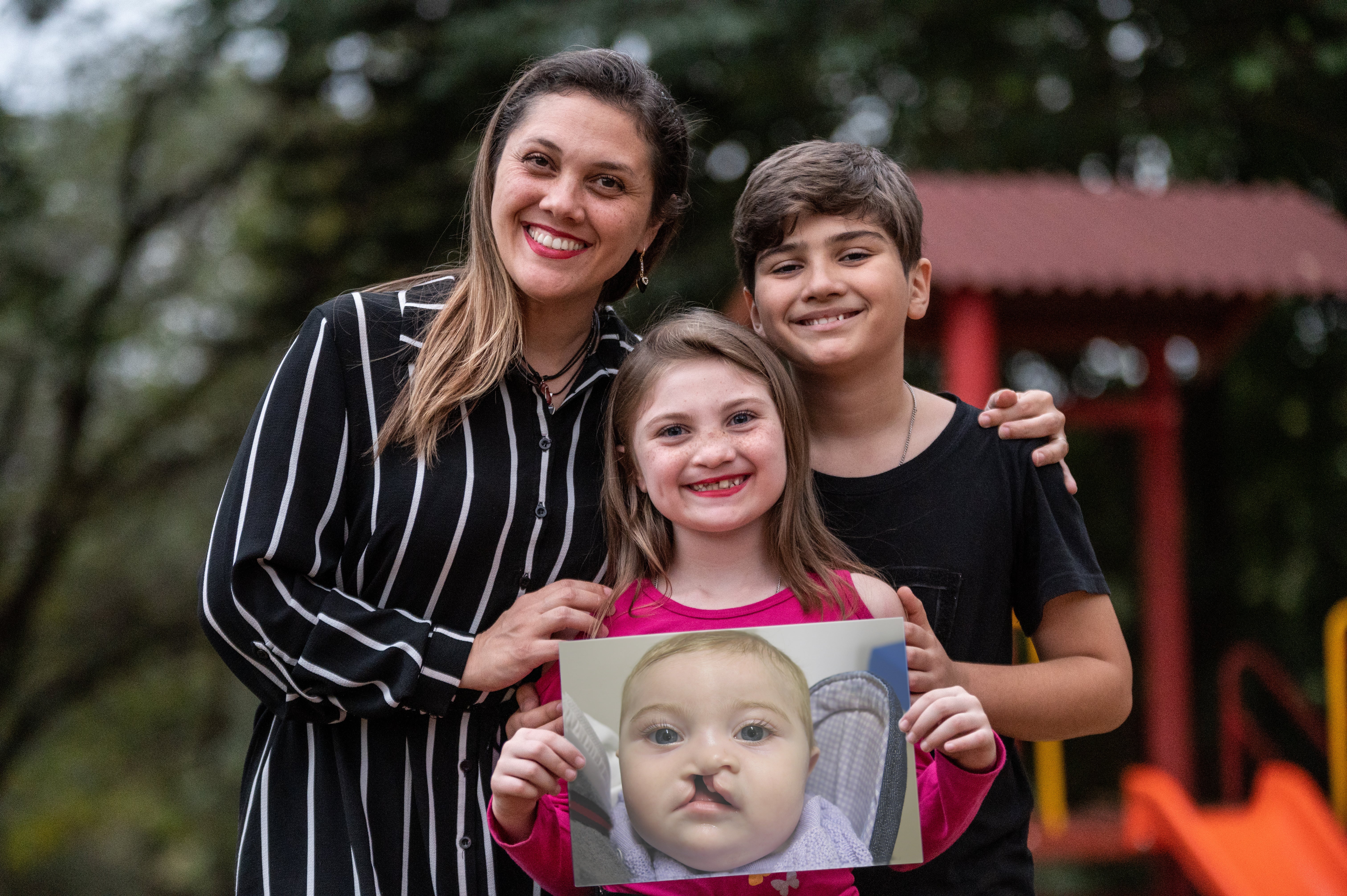 Grazi, Milena und Nilo halten ein Bild von Milena vor ihrer Spalt-OP