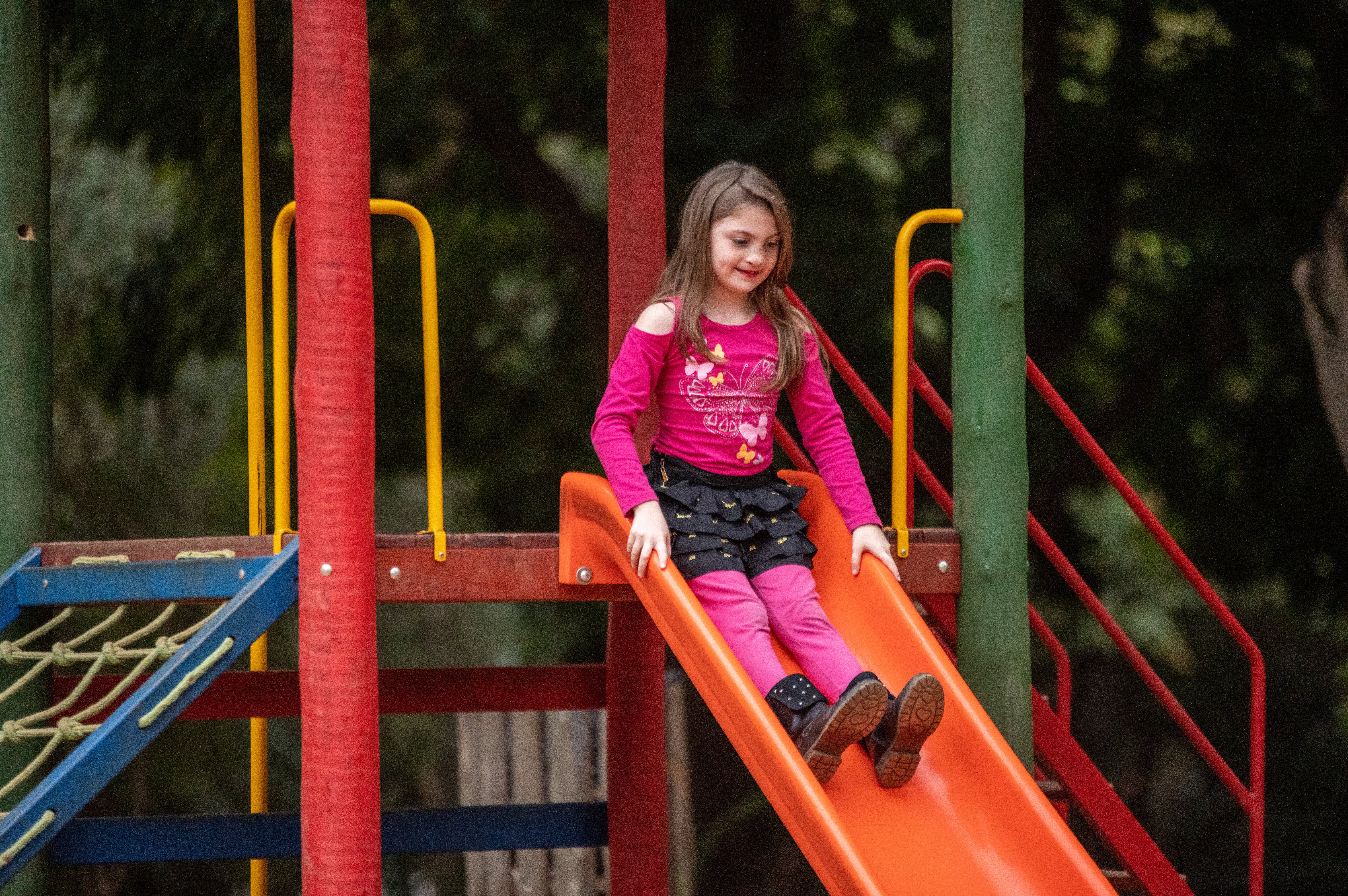 Milena rutscht auf dem Spielplatz eine Rutsche hinunter