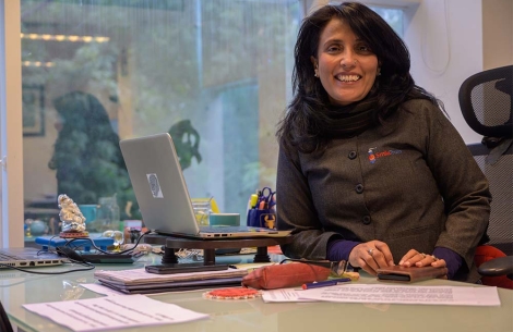 Mamta Carrol sitzt lächelnd an ihrem Schreibtisch