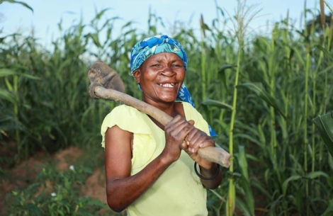 Zita lächelt nach der Spalt-OP und schultert eine Hacke auf ihrem Bauernhof